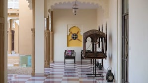 Un intérieur traditionnel avec des arches richement décorées, un sol à carreaux, une chaise en bois et un élément décoratif fixé au mur.