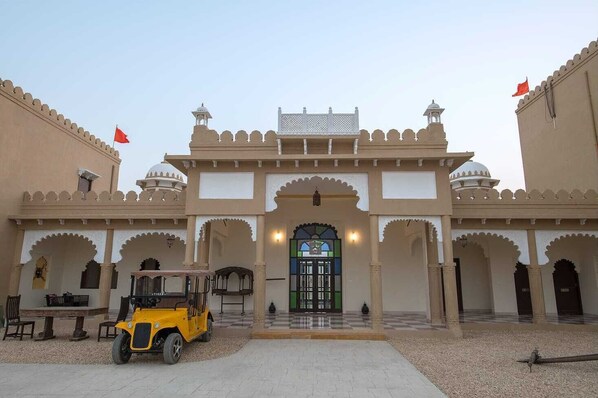 A traditional building with a central entrance, arched doorways, and a tiled courtyard.