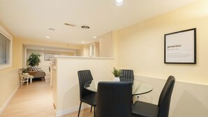 A dining area with a glass table and black chairs, a framed sign on the wall, and a plant on the table. - 2BR Trafalgar Retreat near UBC & Pacific Spirit (Vancouver)
