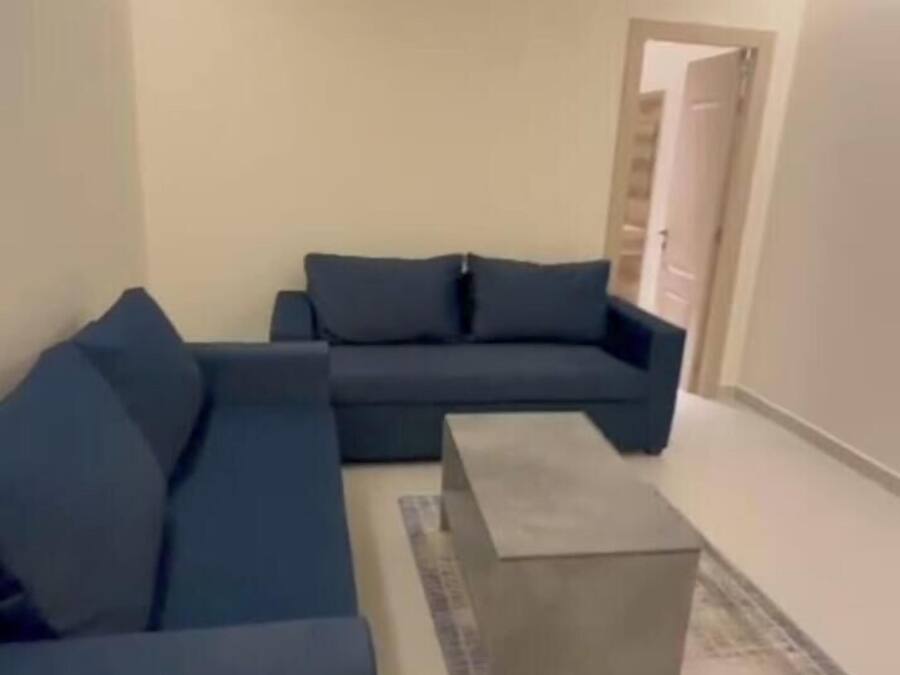 Un salon moderne avec un canapé d’angle, une table basse et un tapis à motifs.
