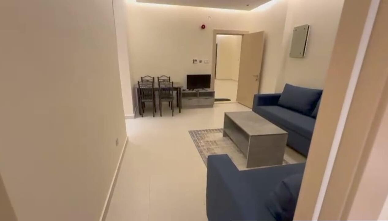 A compact room with a bed, a desk, and a kitchenette.