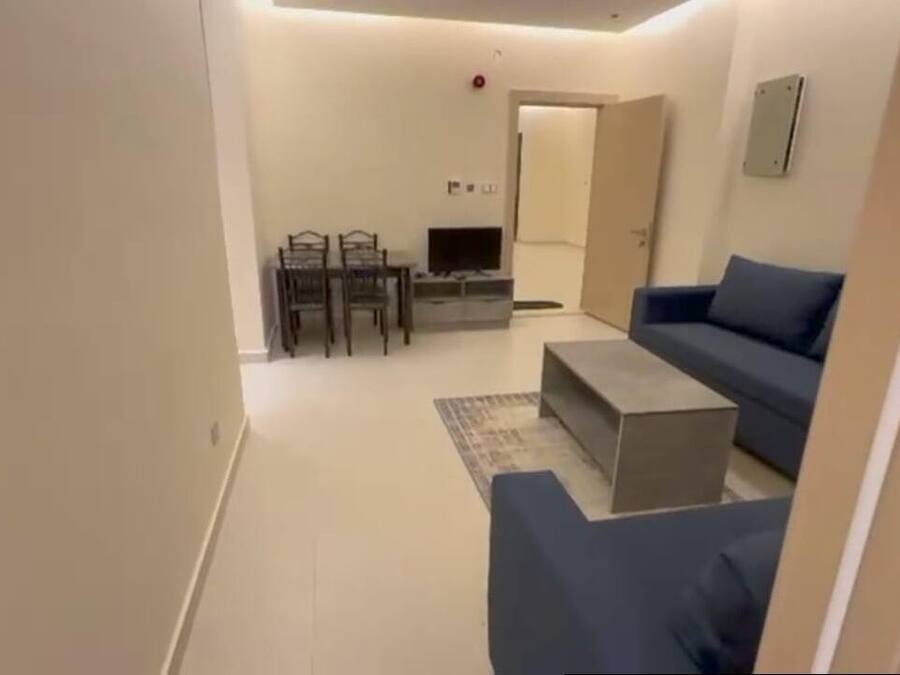 A compact room with a bed, a desk, and a kitchenette.