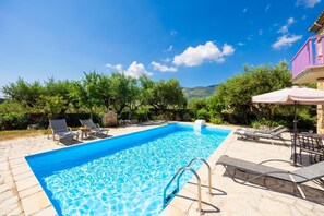 A rectangular swimming pool with clear blue water, surrounded by lounge chairs and a stone patio. - Villa Carolina - Two Bedroom Villa, Sleeps 5 (Agios Dimitrios)