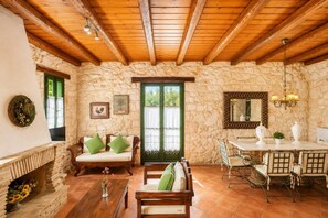 A rustic interior with stone walls, wooden furniture, a fireplace, and a dining area.