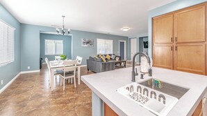A modern kitchen with a large island, a dining area, and a living room. - Quiet Escape: Entire Home with Charming Pool (Coachella)