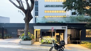 A modern building with a sign reading "TRENDSO BRICKLAI" and a motorcycle parked in front. - Trends Brooklin (São Paulo)