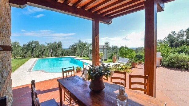 Uma pérgula de madeira com vista para uma piscina e paisagem circundante.