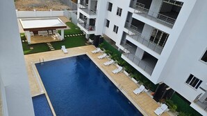 Un edificio moderno con piscina, area salotto all'aperto e balconi.