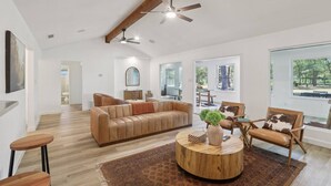 A spacious living room with a large sofa, a round wooden coffee table, and a ceiling fan. - Peaceful Country Escape on 5 Acres with Game Room, BBQ & Outdoor Living (Manor)