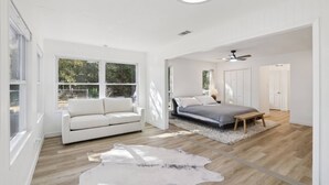 A spacious bedroom with a large bed, a white sofa, and a cowhide rug. - Peaceful Country Escape on 5 Acres with Game Room, BBQ & Outdoor Living (Manor)