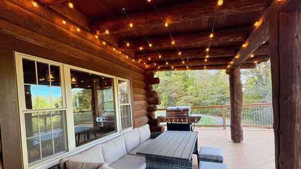 A log cabin with a covered deck featuring a sofa, a grill, and string lights. - VT Lodge Cabin w Mountain Views near Killington (Proctor)