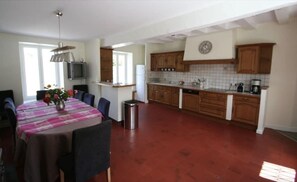 Eine geräumige Küche mit Holzschränken und einer gefliesten Spritzschutzwand, ein Essbereich mit Tisch für vier Personen und ein kleiner Fernseher an der Wand.