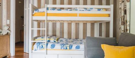 A bunk bed with two levels, a grey sofa, and a wooden floor.