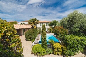 Eine Villa mit Swimmingpool, umgeben von üppiger Vegetation und einem traditionellen Ziegeldach.