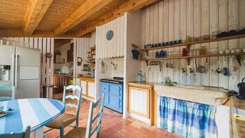 Een keuken met houten balken, een blauw gestreepte tafel en een betegelde vloer.