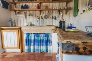 Eine rustikale Küche mit Holzböden, hängendem Kochgeschirr und Fliesenboden.