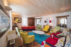 Un salon spacieux avec un plafond en bois, des canapés aux couleurs vives et une table basse centrale.