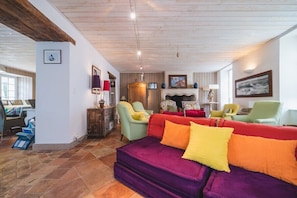A cozy living room with a purple sofa, green armchairs, and a fireplace.