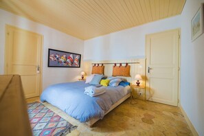 Ein Schlafzimmer mit einem Bett, zwei Nachttischen mit Lampen, einem gemusterten Teppich und einem Bild an der Wand.