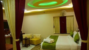 A hotel room with a bed, a desk, a chair, and a window with curtains. - Hotel Bensen (Puri)