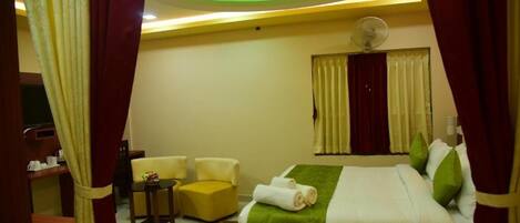 A hotel room with a bed, a desk, a chair, and a window with curtains.