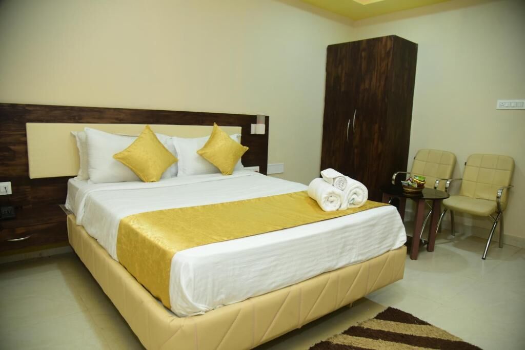 A hotel room with a bed, a wardrobe, two chairs, and a small table.