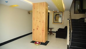 A lobby with a wooden column, a black staircase, and a framed artwork on the wall. - Hotel Bensen (Puri)
