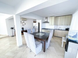 A modern kitchen with light wood cabinets, a built-in oven, and a stainless steel range hood.