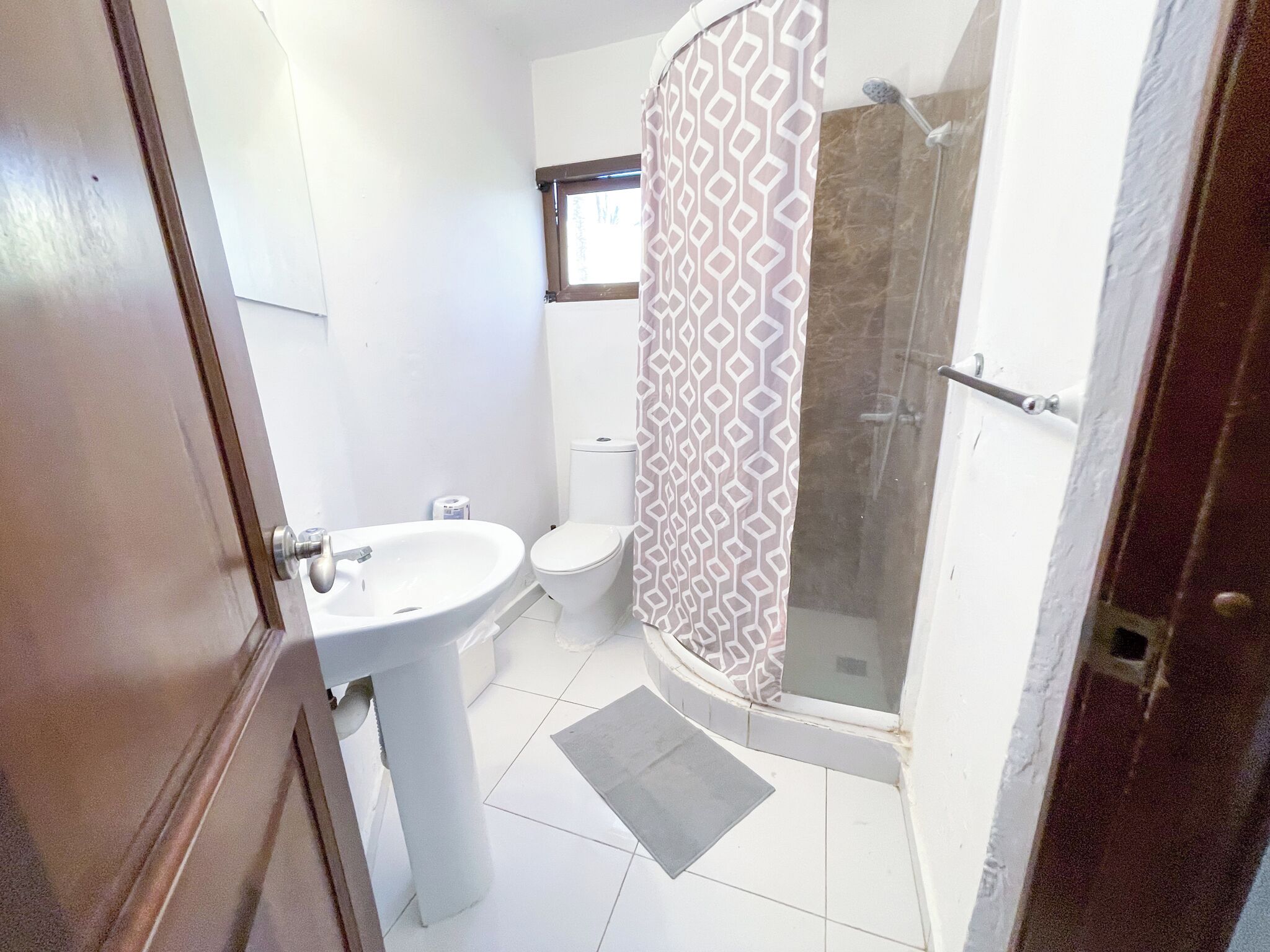 A bathroom with a white sink, toilet, and shower.