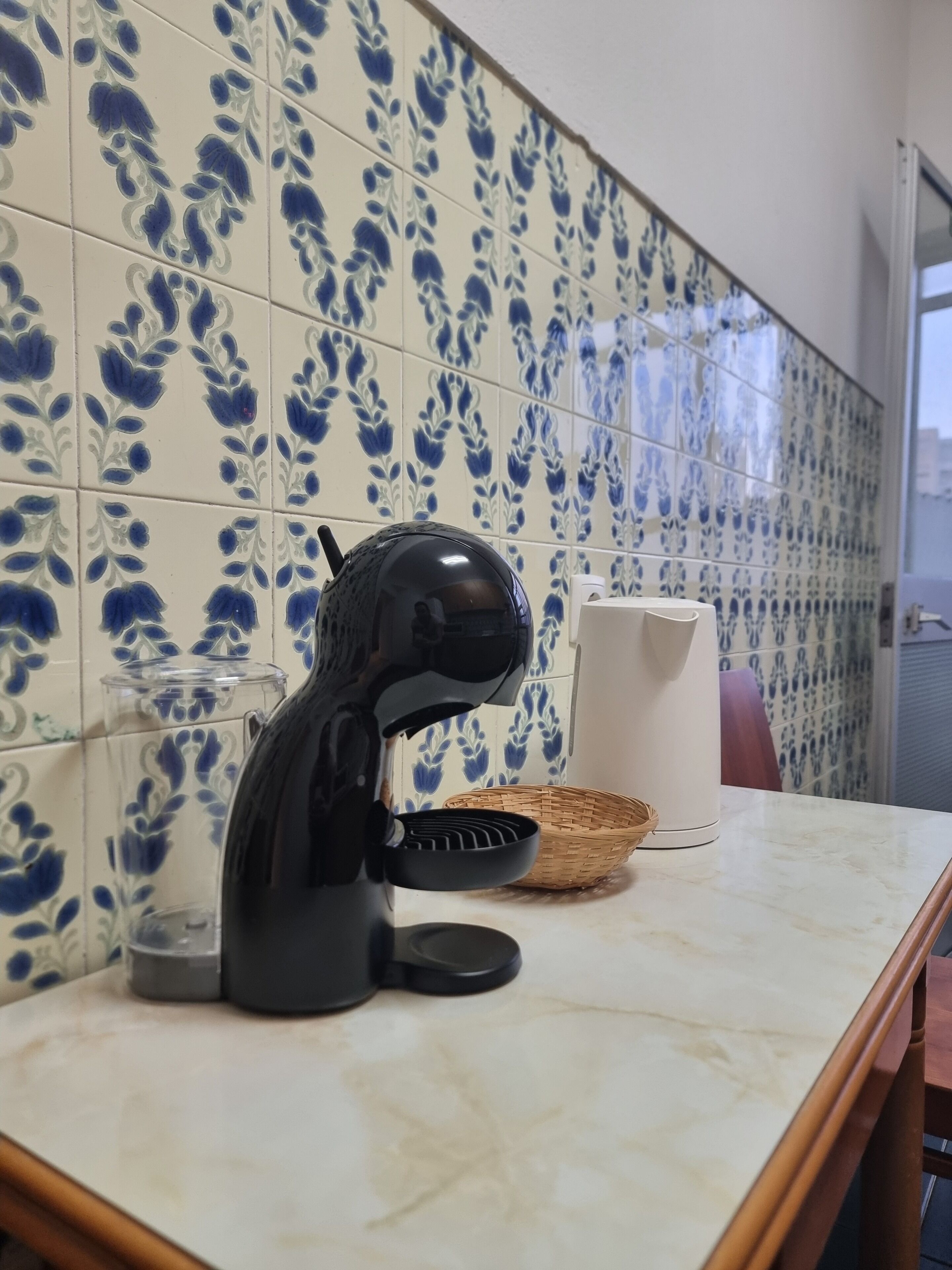 A kitchen with a coffee maker on the counter, a basket, and a roll of paper towels.