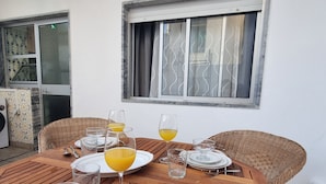 Ein Holzespeisesaal mit Tellern, Gläsern, Besteck, einem Fenster mit Vorhängen und Korbstühlen.