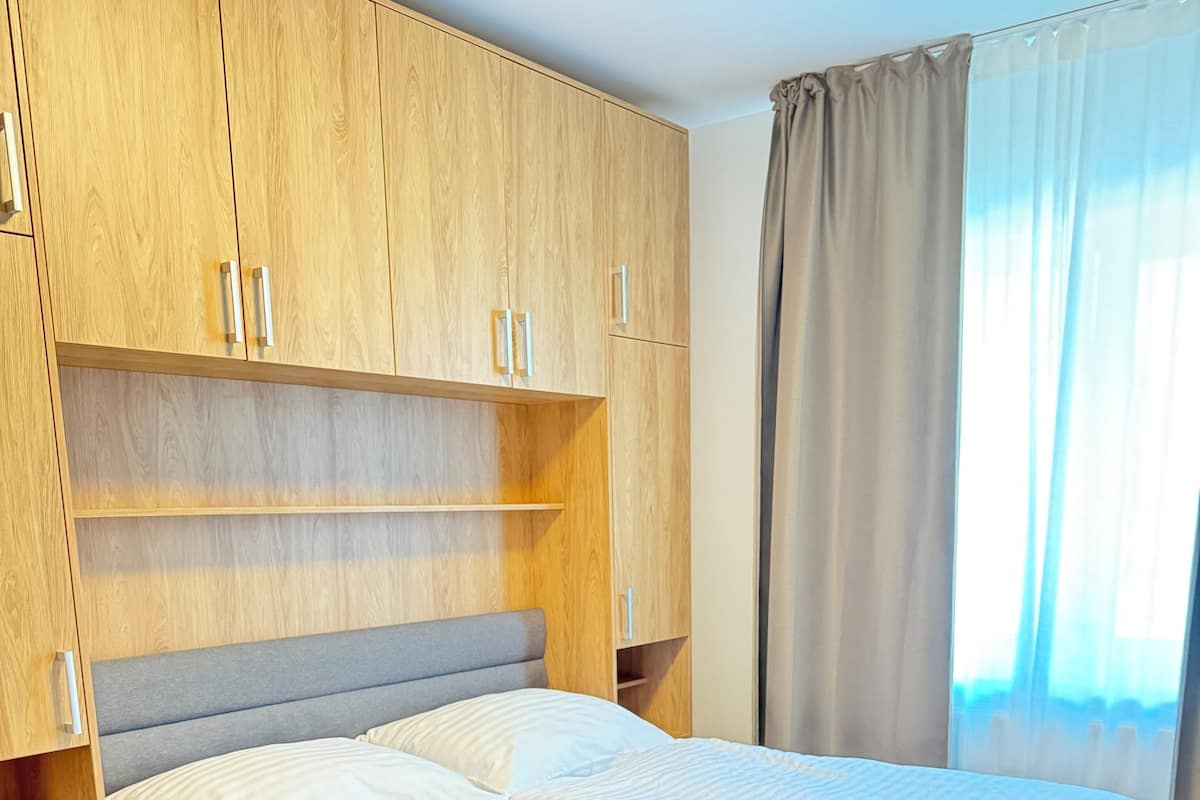 Une chambre moderne avec un grand lit, une armoire en bois et une fenêtre avec des rideaux.