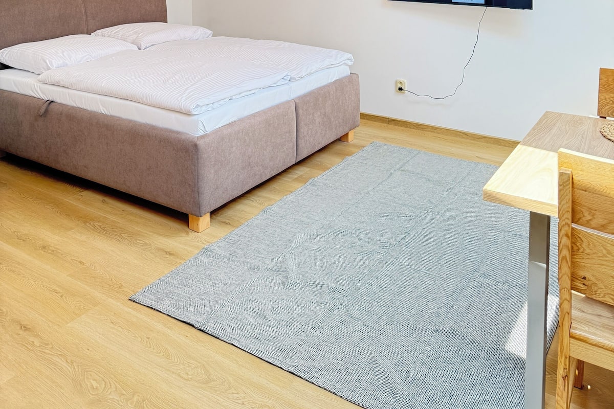 Une chambre à coucher moderne avec un lit, un bureau et un téléviseur fixé au mur.