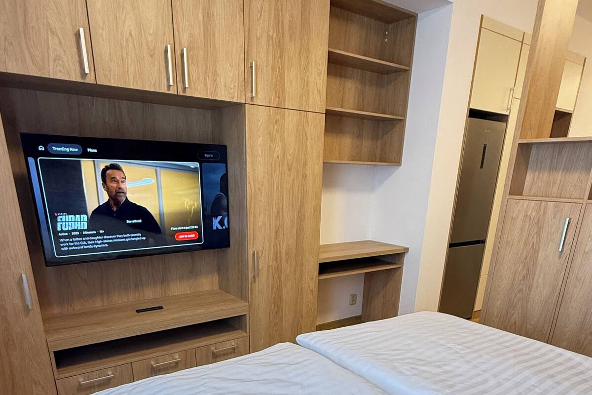 Une chambre à coucher avec un lit, une armoire en bois et un téléviseur diffusant un film.