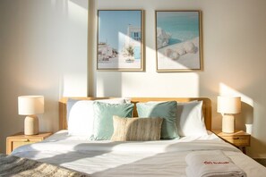 A hotel room with a bed, two nightstands, two lamps, and two framed pictures on the wall.