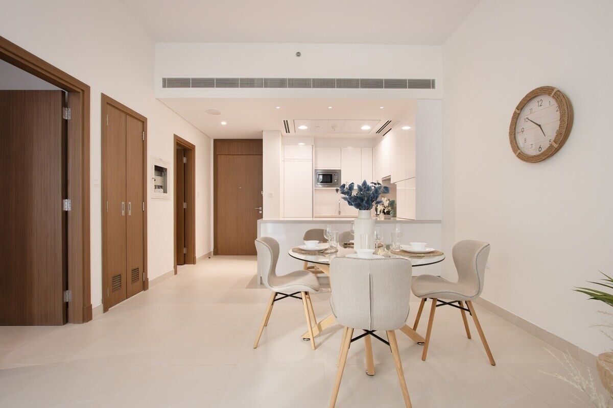 Un'area pranzo moderna con un tavolo rotondo, quattro sedie e una sveglia appesa al muro.