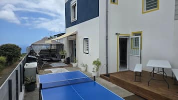 Un edificio residencial con mesa de ping pong azul, zona de estar al aire libre y un porche cubierto.