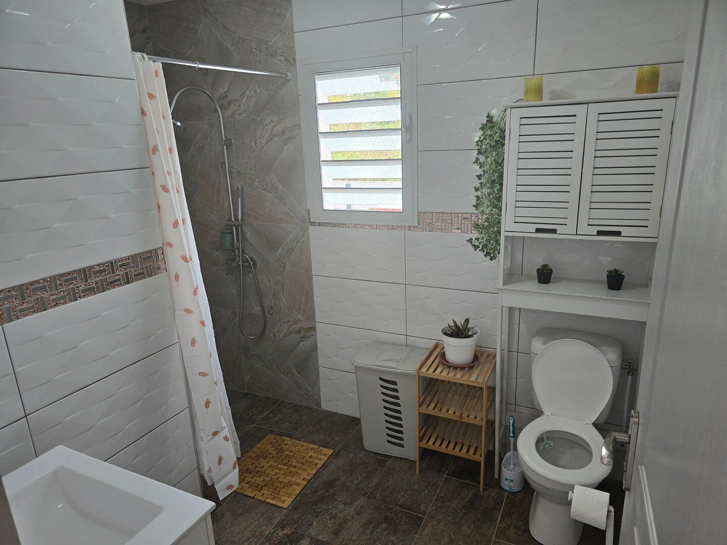 A modern bathroom with a shower, toilet, and sink.