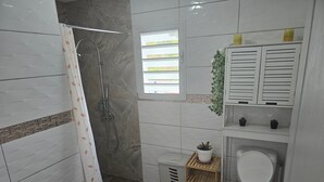 Een moderne badkamer met douche, toilet en wastafel.