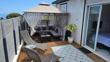 A balcony with a sofa, chairs, a table, and a potted plant.