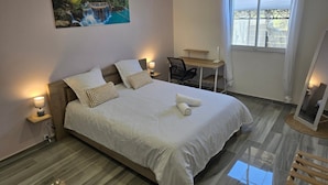 Hotelkamer met een bed, bedlampen, een bureau, een stoel, een schilderij en een raam met uitzicht.