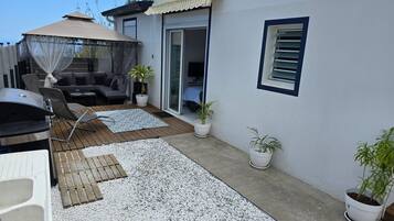 Un patio con una parrilla, mobiliario exterior y plantas en macetas.