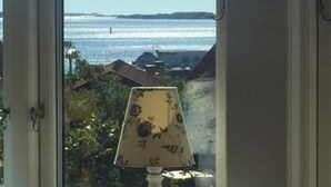 A window with a view of the sea and a lamp on the windowsill.