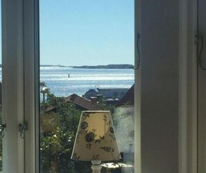 Ein Fenster mit Meerblick und einer Lampe auf der Fensterbank.