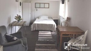 A bedroom with a bed, a small table with a plant, a chair, a desk, and a window. - Newly renovated turn-of-the-century house with sea views (Lysekil)