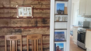 A cozy kitchen with wooden walls, a bookshelf with books, and a dining area with two chairs. - Newly renovated turn-of-the-century house with sea views (Lysekil)