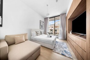 Habitación de hotel moderna con una cama, un sofá, un televisor y vistas a la ciudad.