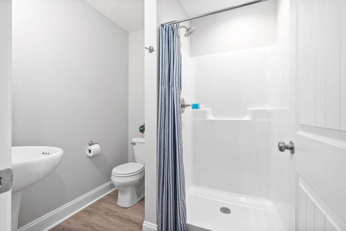 A bathroom with a shower, toilet, and sink.