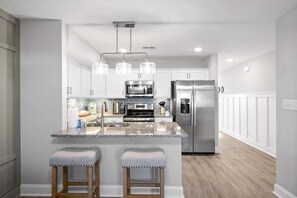 A modern kitchen with a central island, stainless steel appliances, and pendant lighting. - Henry Place Boulevard (Clarksville)