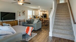 A modern living room with a grey sofa, a flat-screen TV, and a ceiling fan. A staircase leads to an upper level. - Franklin Street (Clarksville)